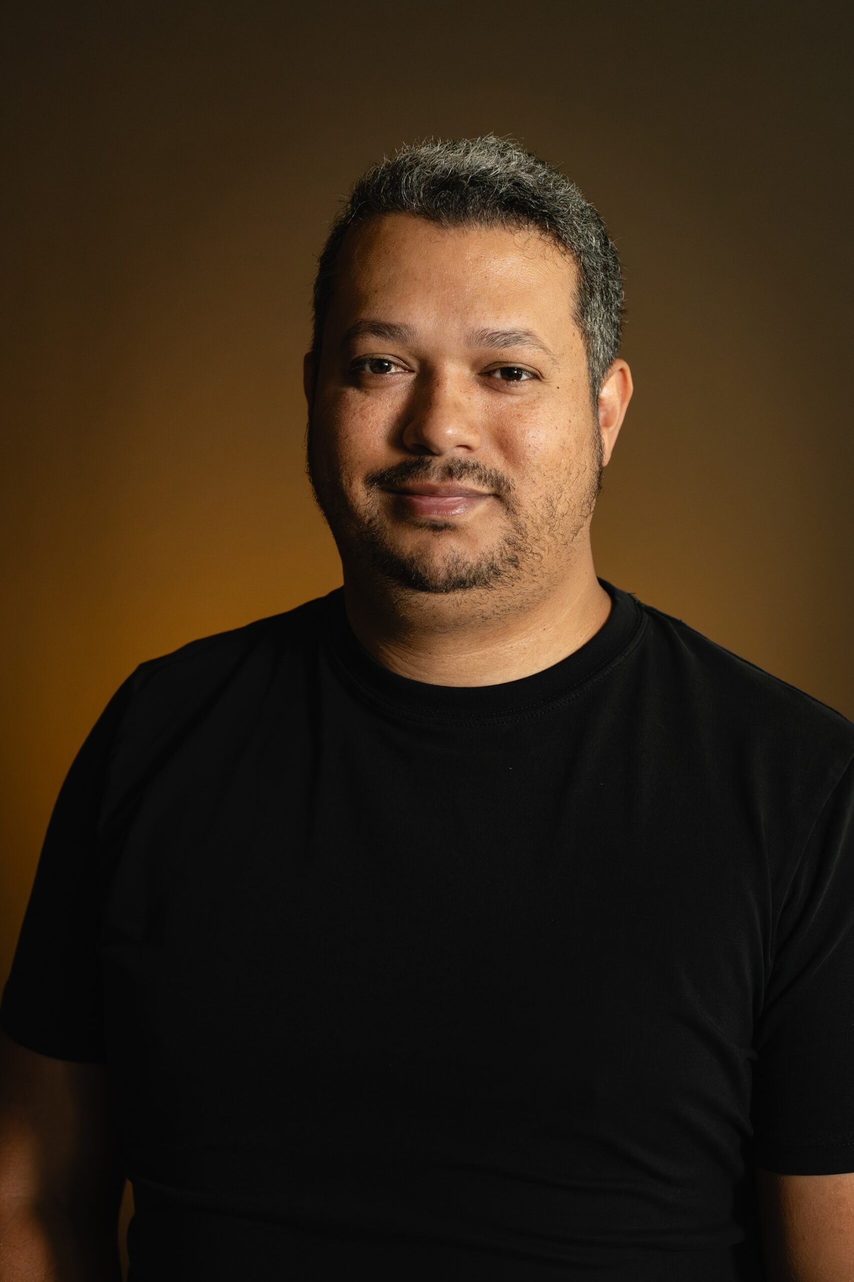 Portrait of Rodrigo Chaves against a warm amber background